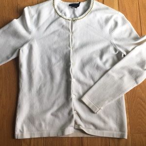 White sweater with green trim around neckline